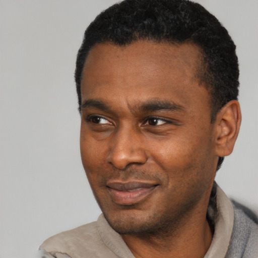 Joyful black young-adult male with short  black hair and brown eyes