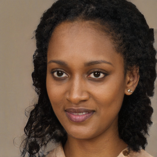 Joyful black young-adult female with long  black hair and brown eyes