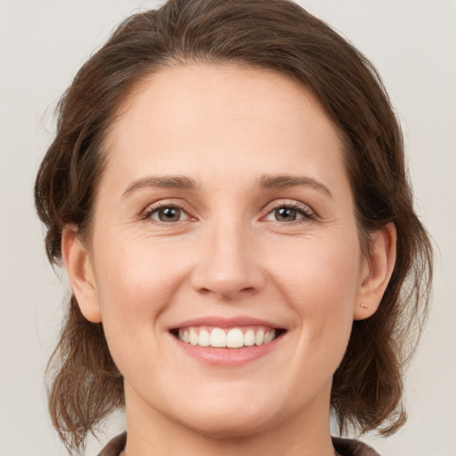 Joyful white young-adult female with medium  brown hair and grey eyes