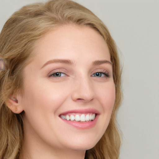 Joyful white young-adult female with long  brown hair and blue eyes