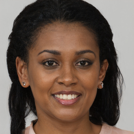Joyful black young-adult female with long  brown hair and brown eyes