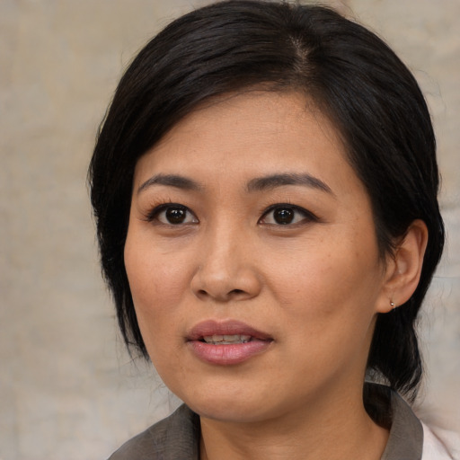 Joyful asian adult female with medium  black hair and brown eyes