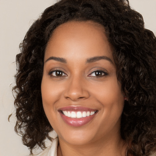 Joyful black young-adult female with long  brown hair and brown eyes