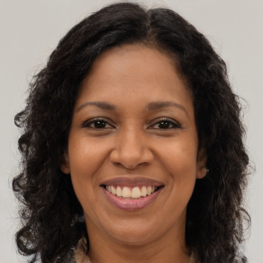 Joyful black adult female with long  brown hair and brown eyes
