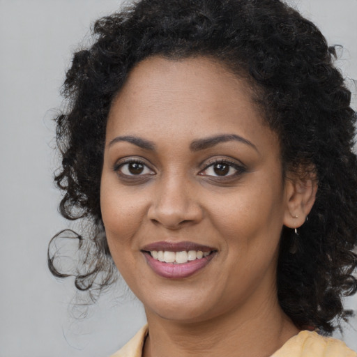 Joyful black young-adult female with long  brown hair and brown eyes