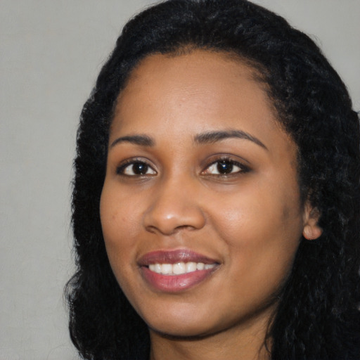 Joyful black young-adult female with long  black hair and brown eyes