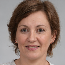 Joyful white adult female with medium  brown hair and blue eyes