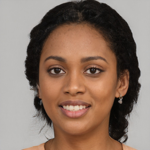 Joyful black young-adult female with long  black hair and brown eyes