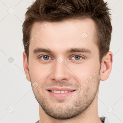 Joyful white young-adult male with short  brown hair and grey eyes