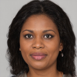 Joyful black adult female with long  brown hair and brown eyes