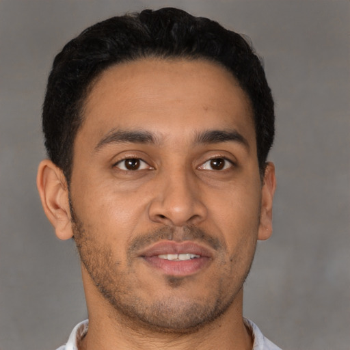 Joyful latino young-adult male with short  brown hair and brown eyes