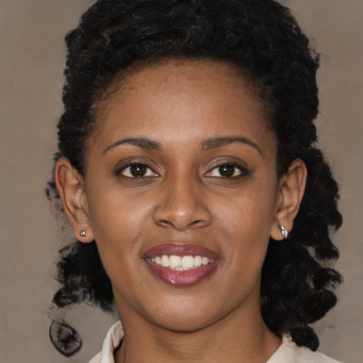 Joyful black young-adult female with long  black hair and brown eyes