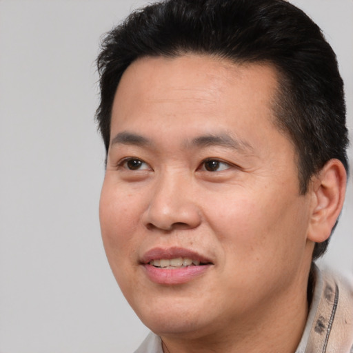 Joyful asian adult male with short  brown hair and brown eyes