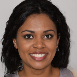 Joyful black young-adult female with long  brown hair and brown eyes