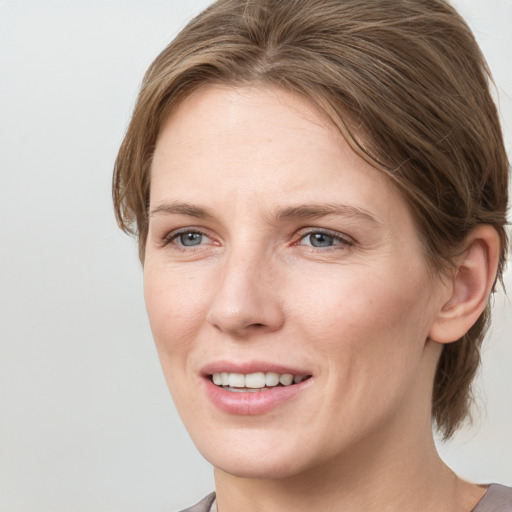 Joyful white young-adult female with medium  brown hair and grey eyes