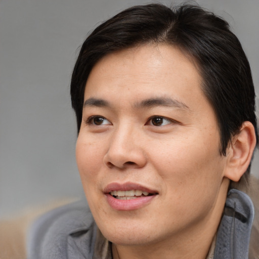 Joyful asian adult male with short  brown hair and brown eyes