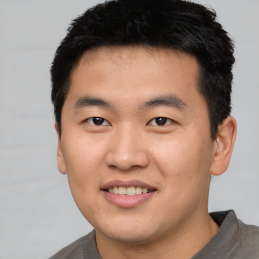 Joyful asian young-adult male with short  black hair and brown eyes