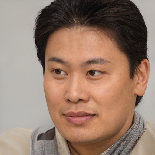 Joyful asian young-adult male with short  brown hair and brown eyes