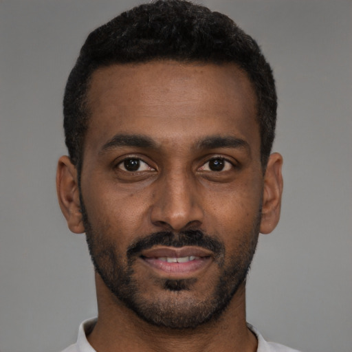 Joyful black young-adult male with short  black hair and brown eyes