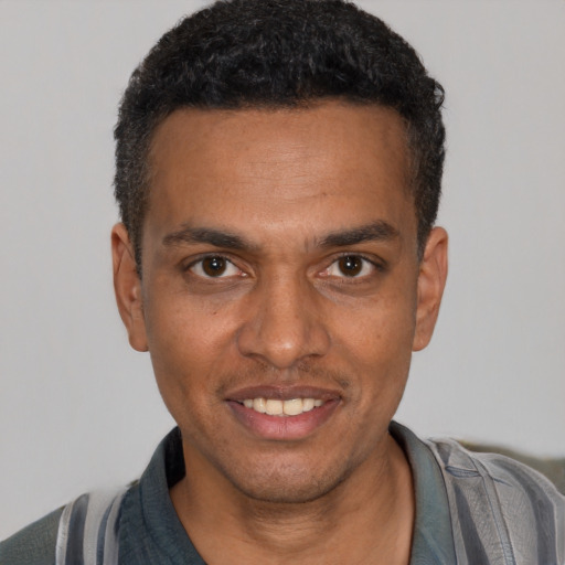 Joyful black young-adult male with short  black hair and brown eyes