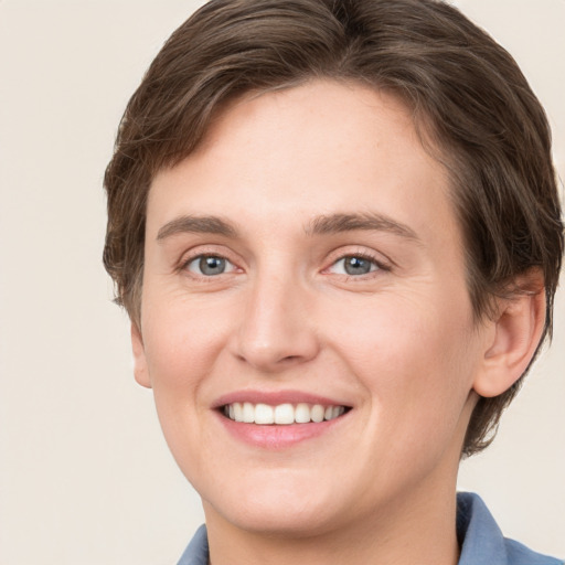 Joyful white young-adult female with short  brown hair and grey eyes