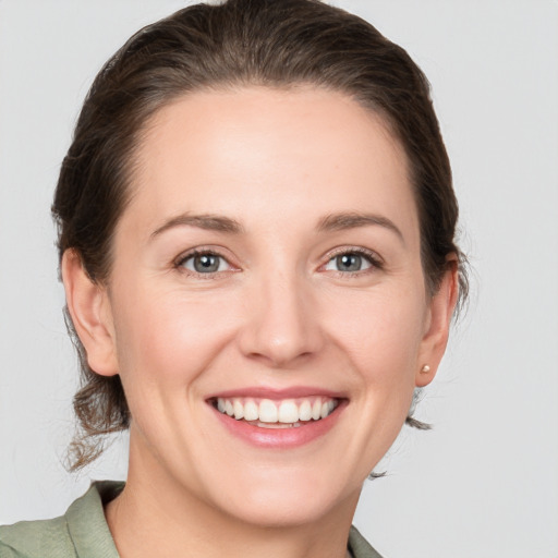 Joyful white young-adult female with medium  brown hair and grey eyes