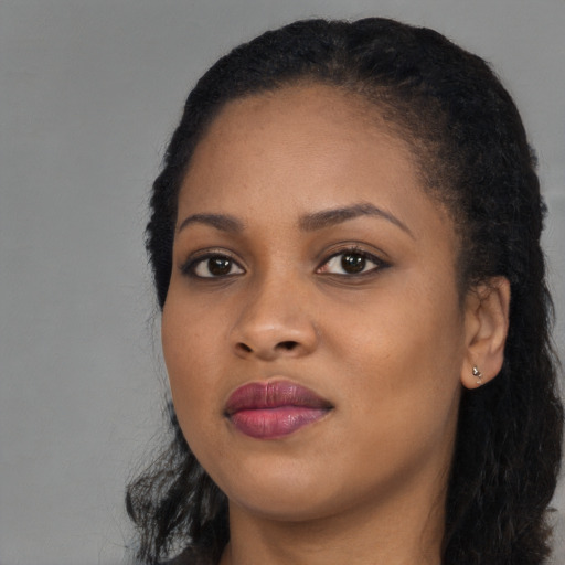 Joyful black young-adult female with long  black hair and brown eyes