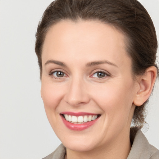 Joyful white young-adult female with medium  brown hair and grey eyes