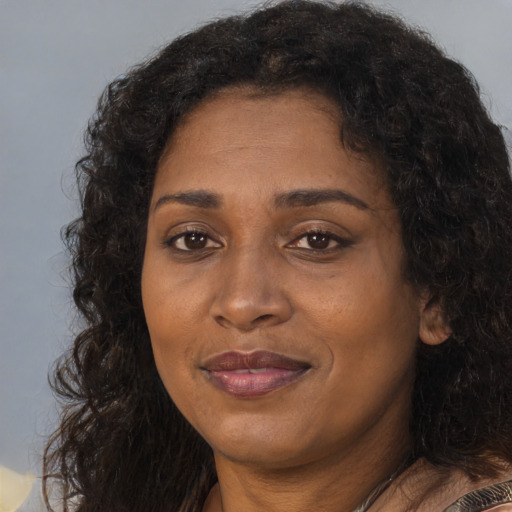 Joyful black adult female with long  brown hair and brown eyes