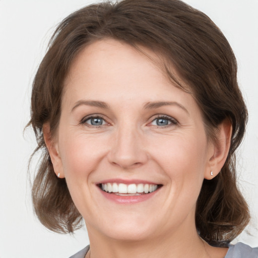 Joyful white young-adult female with medium  brown hair and grey eyes