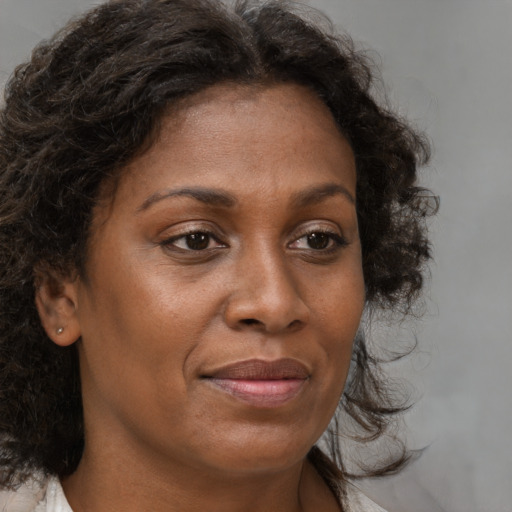 Joyful black adult female with medium  brown hair and brown eyes