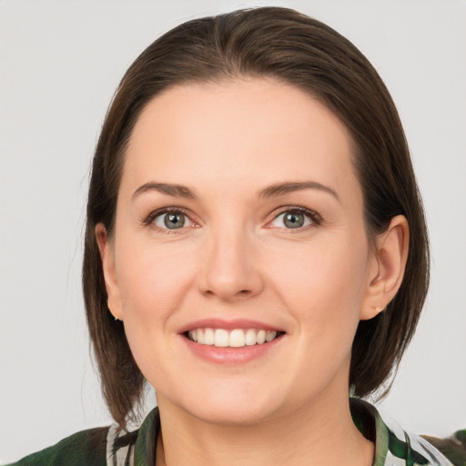 Joyful white young-adult female with medium  brown hair and grey eyes