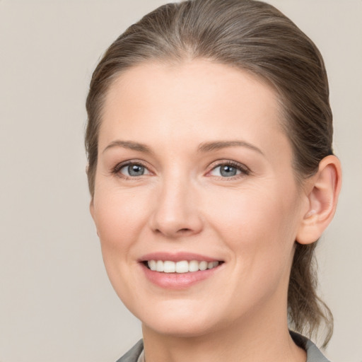 Joyful white young-adult female with medium  brown hair and grey eyes