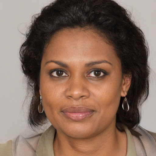 Joyful black young-adult female with long  brown hair and brown eyes