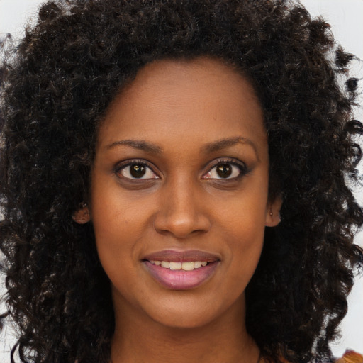 Joyful black young-adult female with long  brown hair and brown eyes