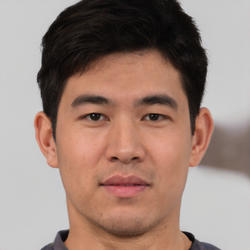 Joyful asian young-adult male with short  black hair and brown eyes