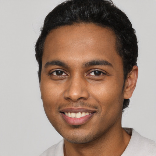 Joyful black young-adult male with short  black hair and brown eyes