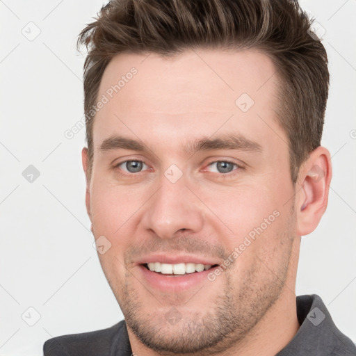 Joyful white young-adult male with short  brown hair and grey eyes