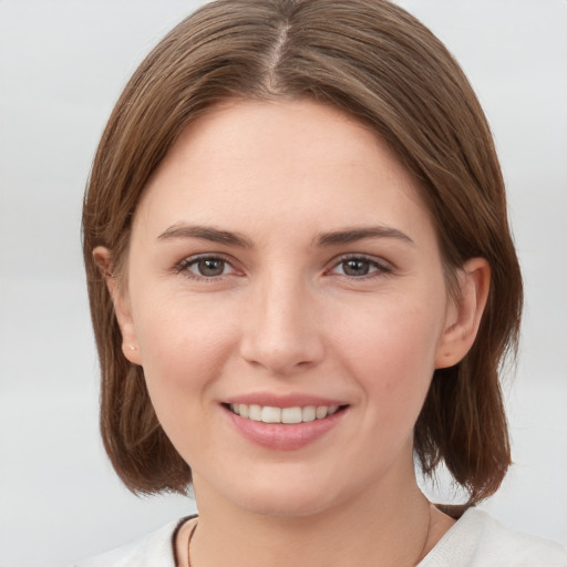 Joyful white young-adult female with medium  brown hair and grey eyes