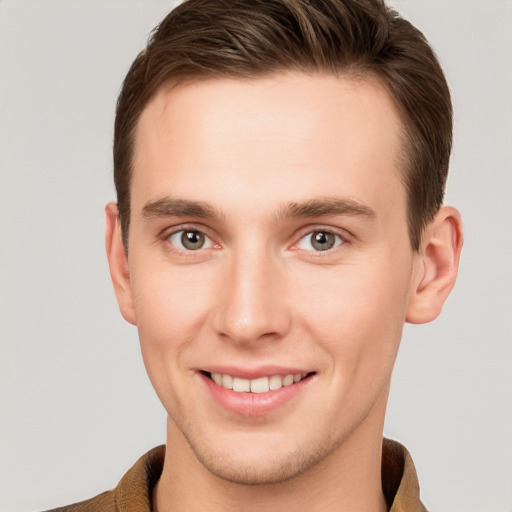 Joyful white young-adult male with short  brown hair and grey eyes