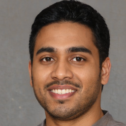 Joyful latino young-adult male with short  black hair and brown eyes