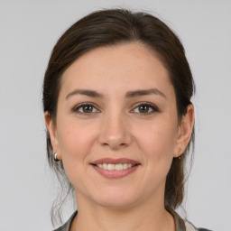 Joyful white young-adult female with medium  brown hair and grey eyes