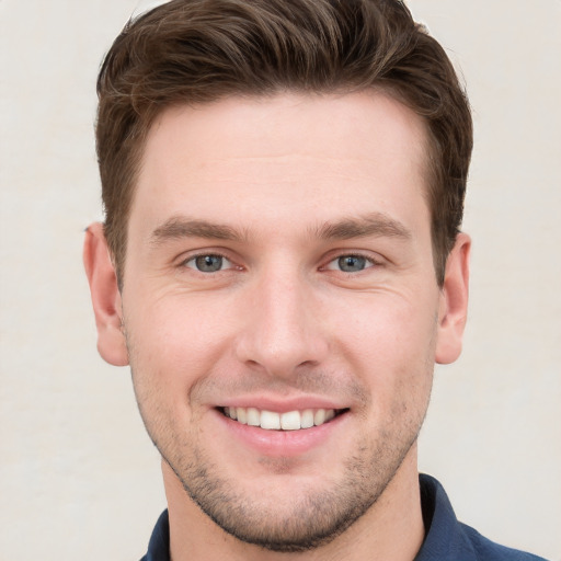 Joyful white young-adult male with short  brown hair and grey eyes