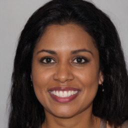 Joyful black young-adult female with long  brown hair and brown eyes