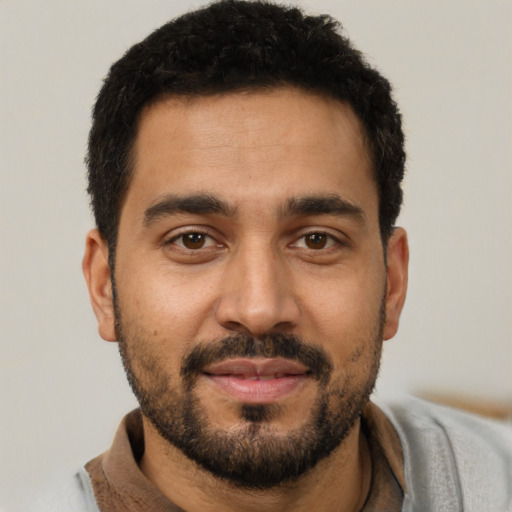 Joyful latino young-adult male with short  black hair and brown eyes