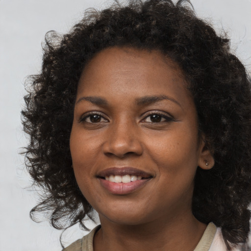 Joyful black young-adult female with long  brown hair and brown eyes