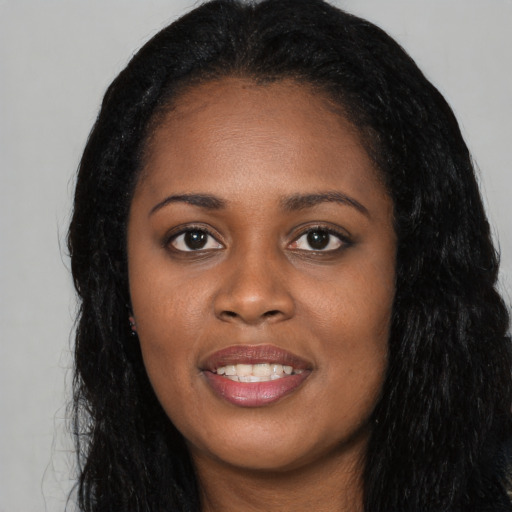 Joyful black young-adult female with long  black hair and brown eyes