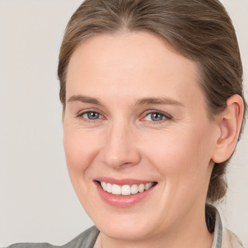 Joyful white young-adult female with medium  brown hair and grey eyes