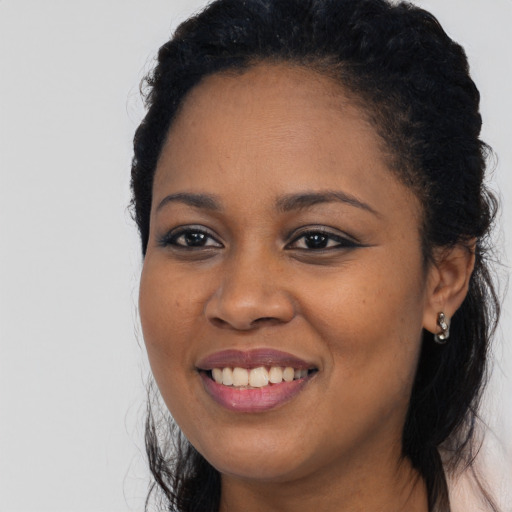 Joyful black young-adult female with long  black hair and brown eyes