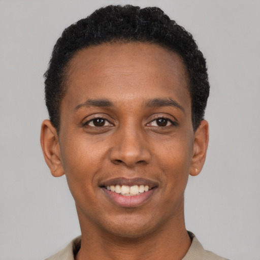 Joyful black young-adult male with short  black hair and brown eyes